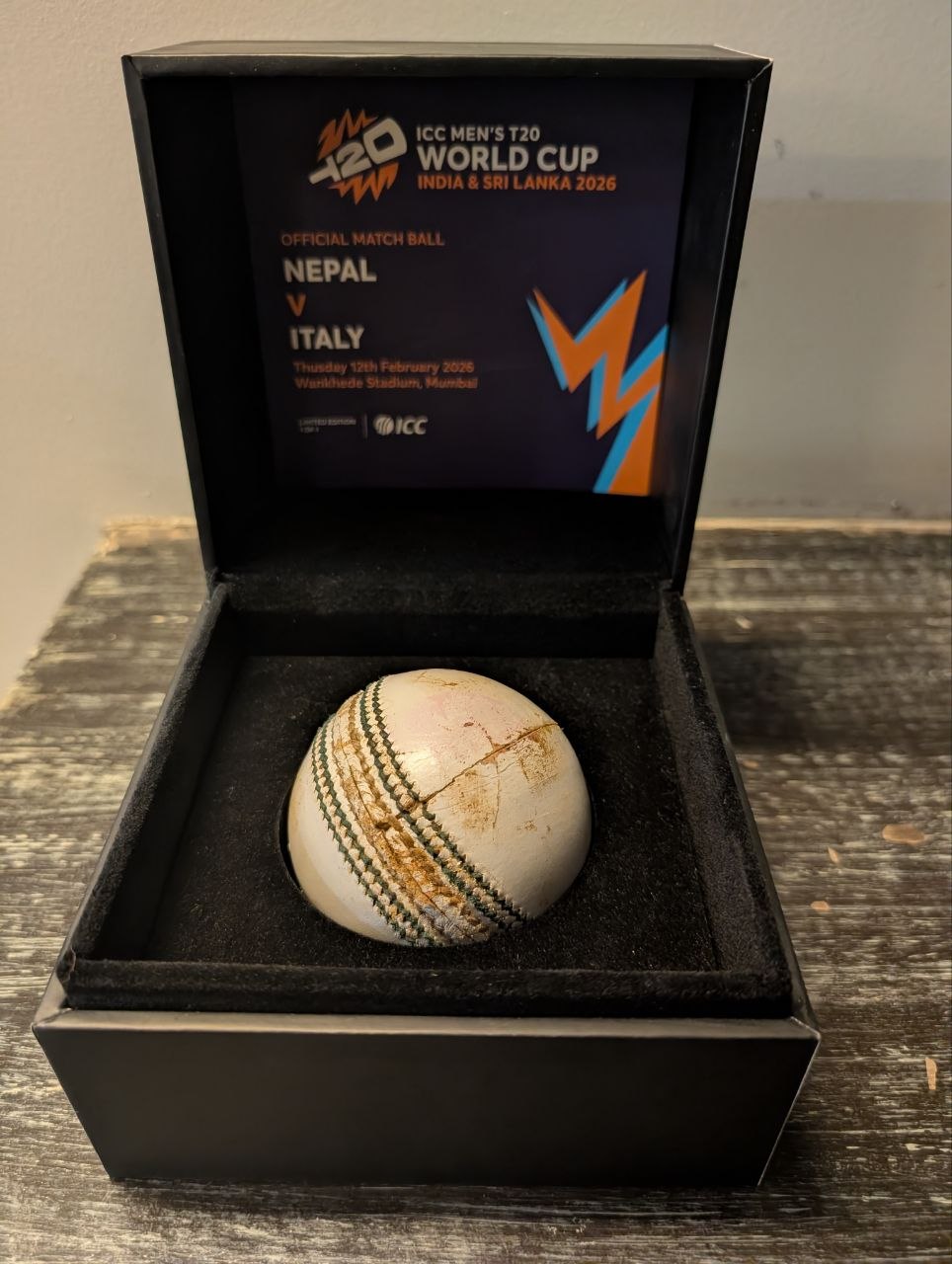 Official ICC Match Ball — Nepal vs Italy T20 World Cup 2026, Wankhede Stadium. White Kookaburra ball in presentation box showing match wear after 19.3 overs.