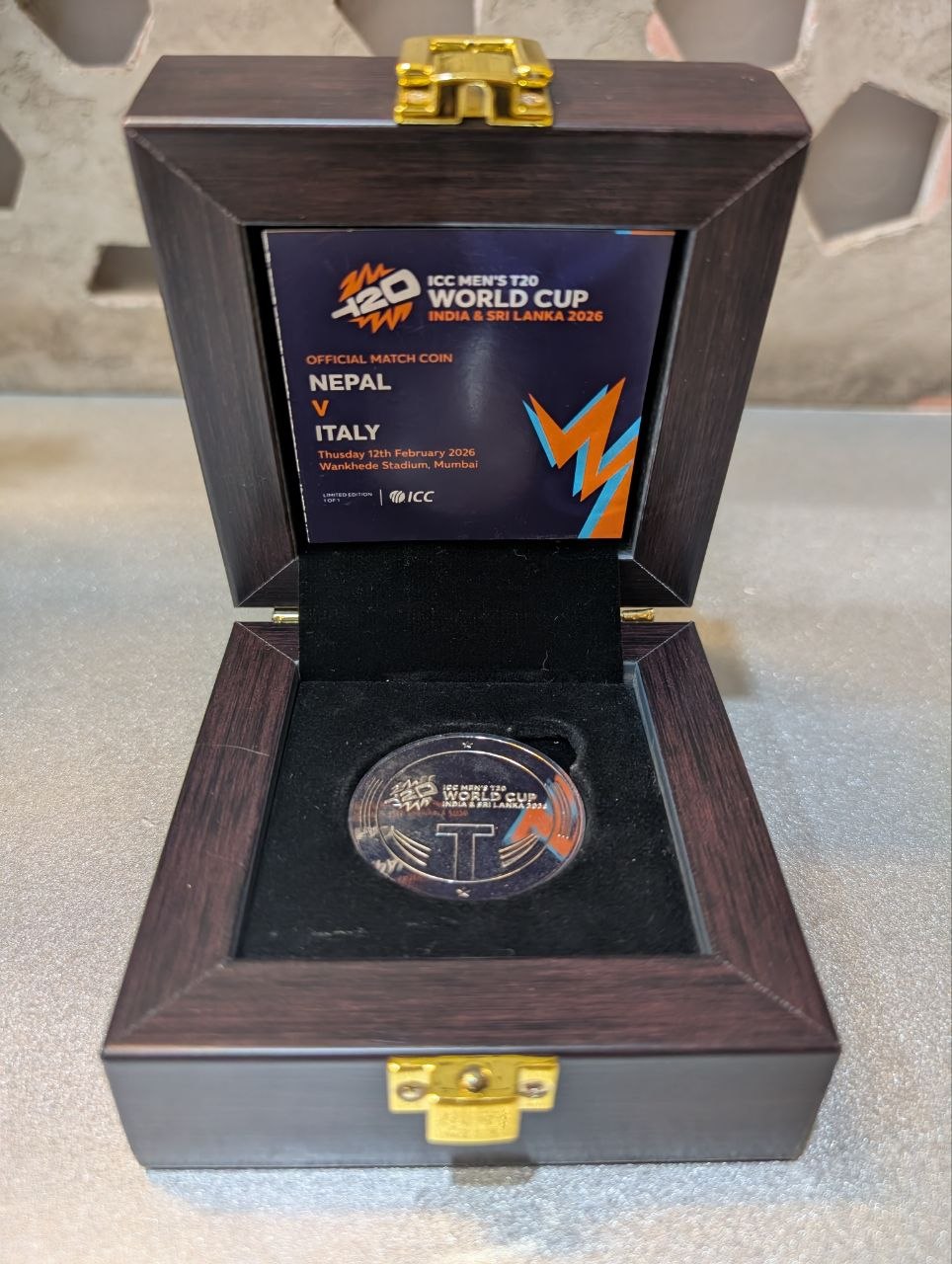 Official ICC Toss Coin — Nepal vs Italy T20 World Cup 2026, in wooden presentation box with gold clasps.